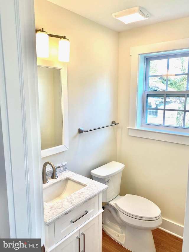 bathroom featuring wood-type flooring, vanity, and toilet