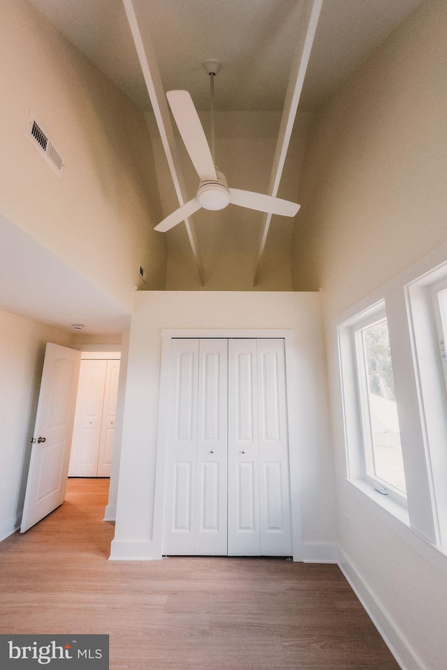 interior space featuring ceiling fan, light wood-type flooring, a closet, and high vaulted ceiling