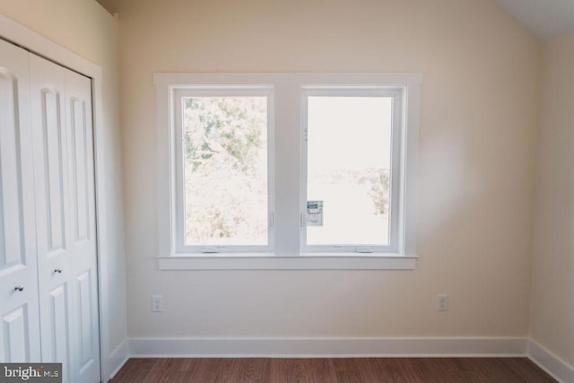 unfurnished bedroom with lofted ceiling, a closet, and dark wood-type flooring