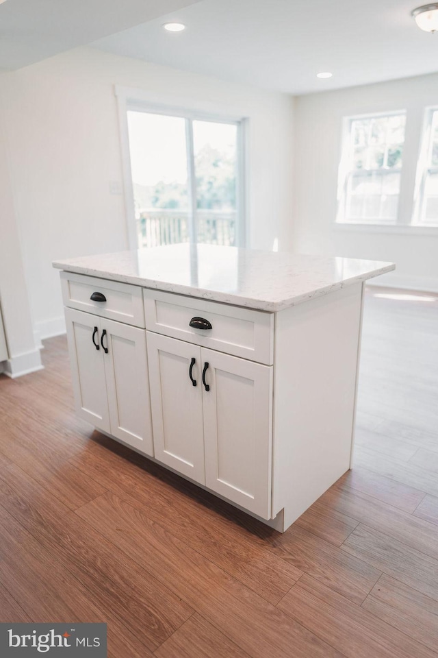 kitchen featuring light wood-type flooring, a kitchen island, and white cabinets