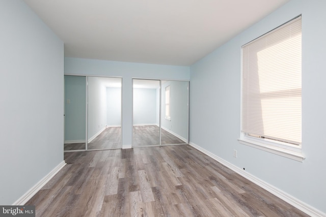 unfurnished bedroom featuring multiple closets and hardwood / wood-style flooring