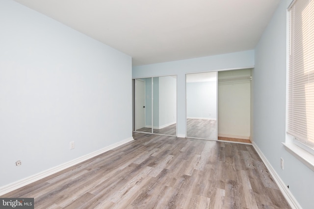 unfurnished bedroom featuring multiple closets and light hardwood / wood-style flooring