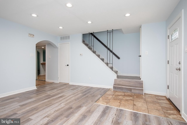 foyer entrance featuring arched walkways, recessed lighting, visible vents, light wood-style floors, and stairway