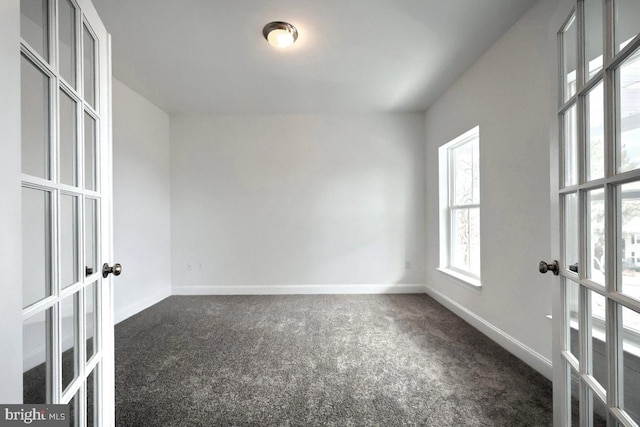 spare room featuring french doors, baseboards, and dark carpet