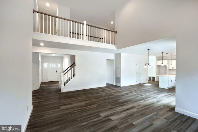 unfurnished living room featuring visible vents, baseboards, dark wood finished floors, and stairs