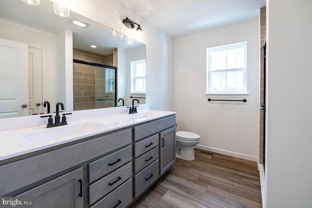 bathroom with a shower stall, wood finished floors, baseboards, and a sink