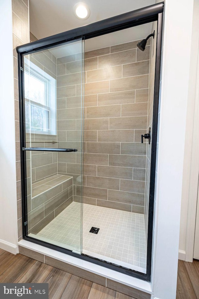 bathroom with a stall shower, baseboards, and wood finished floors