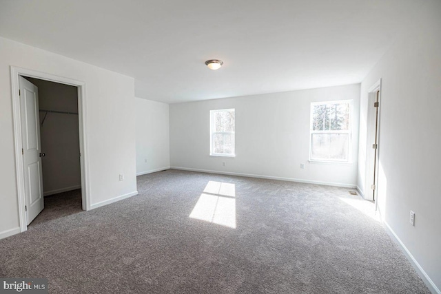 unfurnished bedroom featuring a spacious closet, carpet flooring, and baseboards