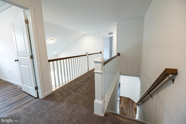 hall featuring lofted ceiling, an upstairs landing, visible vents, and carpet floors