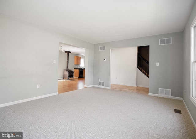 4116 Harford Creamery Rd, White Hall, MD 21161 - unfurnished living room featuring light carpet, a wood stove, and visible vents