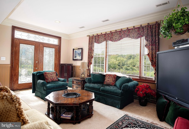 living room with wood walls, ornamental molding, light carpet, and french doors