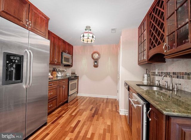 kitchen featuring light wood-type flooring, dark stone counters, sink, and stainless steel appliances