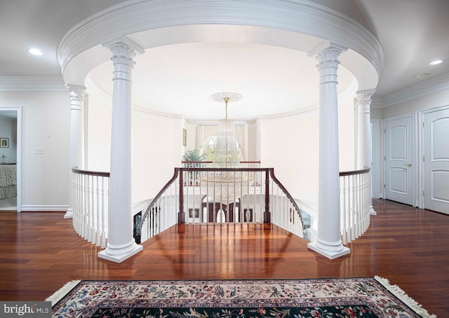 corridor featuring a notable chandelier, dark hardwood / wood-style floors, and ornate columns