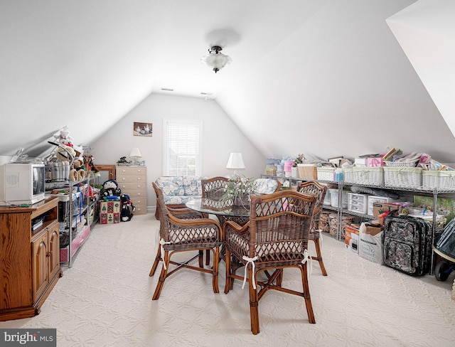 carpeted dining space with lofted ceiling