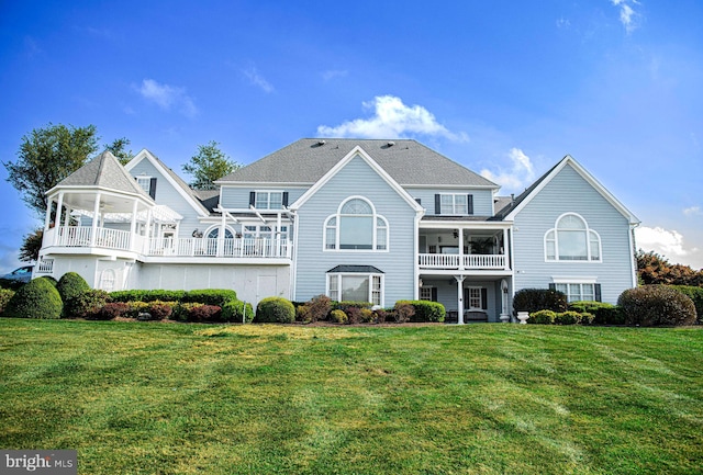 rear view of property featuring a balcony and a yard