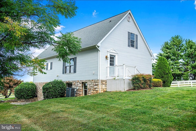 view of property exterior with central AC unit and a yard