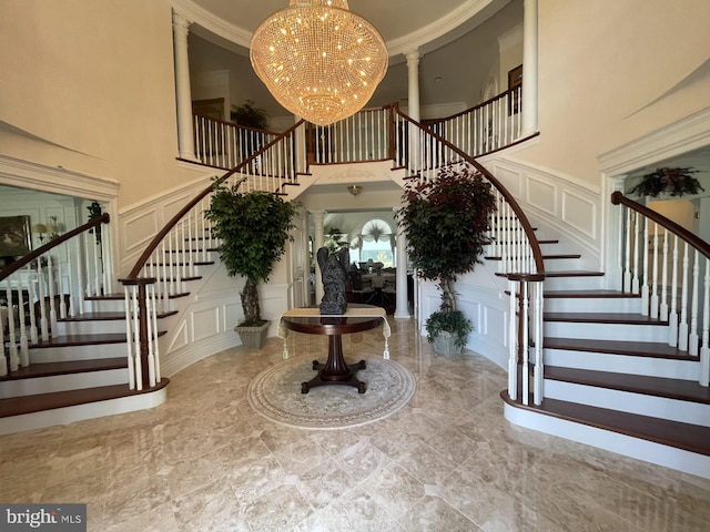 foyer with crown molding, a towering ceiling, and a chandelier