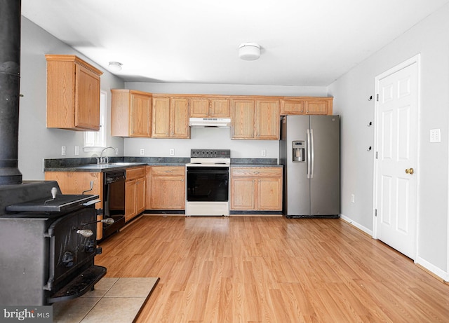 kitchen featuring a wood stove, stainless steel refrigerator with ice dispenser, dishwasher, electric stove, and light hardwood / wood-style floors