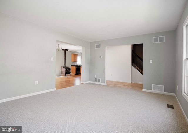 unfurnished room with carpet and a wood stove