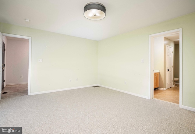 unfurnished bedroom with light carpet and ensuite bath