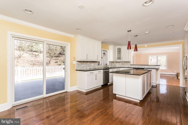 kitchen featuring hanging light fixtures, dark wood-type flooring, decorative backsplash, stainless steel dishwasher, and kitchen peninsula