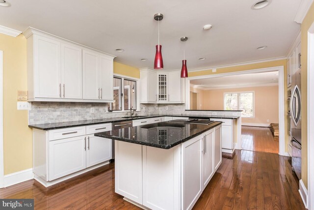 kitchen featuring backsplash, a center island, hanging light fixtures, dark hardwood / wood-style flooring, and stainless steel appliances