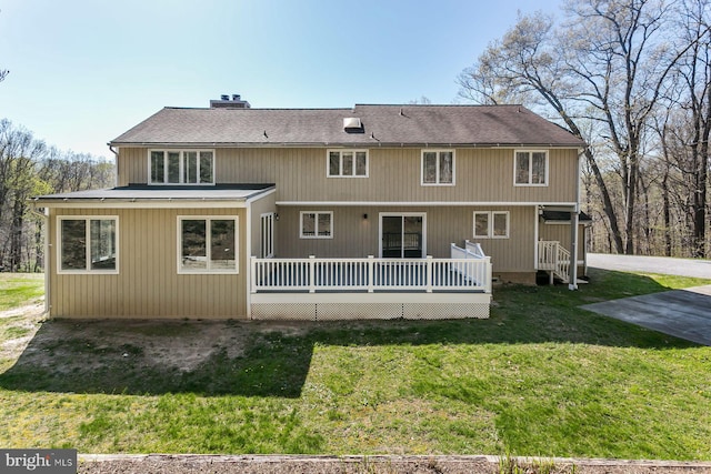 rear view of property featuring a yard and a wooden deck