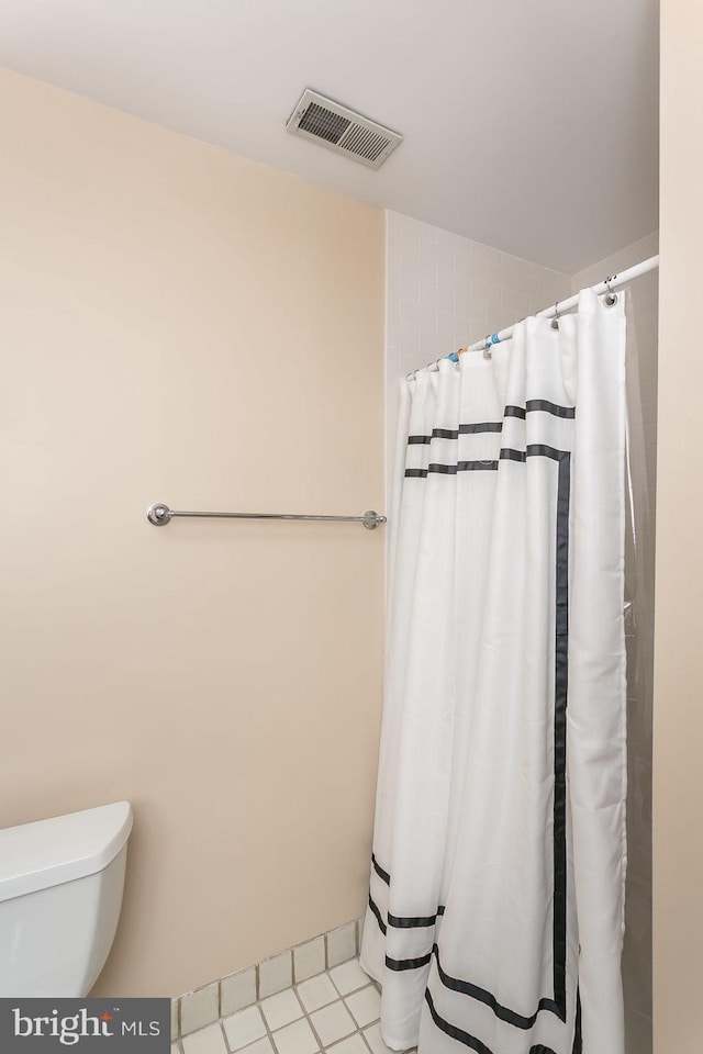 bathroom featuring toilet, a shower with curtain, and tile patterned floors