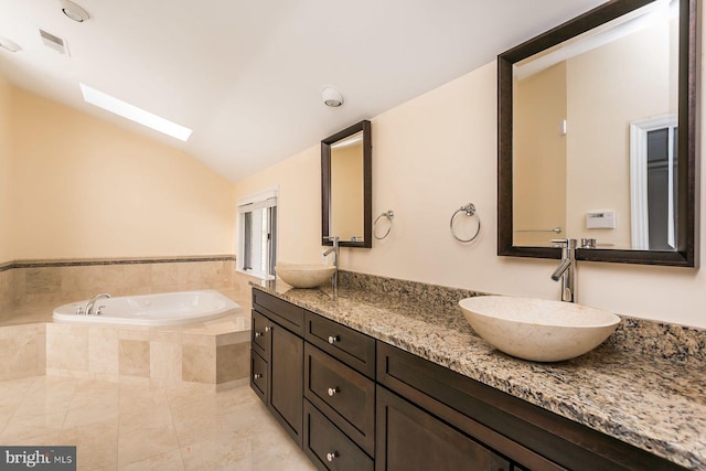 bathroom featuring tiled bath, lofted ceiling with skylight, tile patterned floors, and vanity