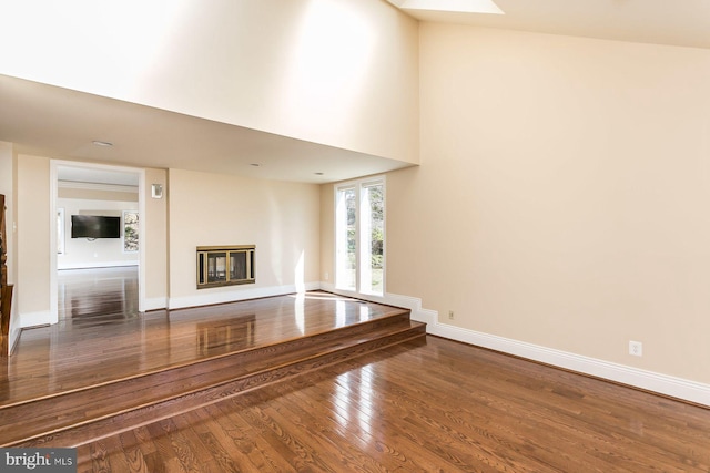 unfurnished living room with a towering ceiling and hardwood / wood-style floors