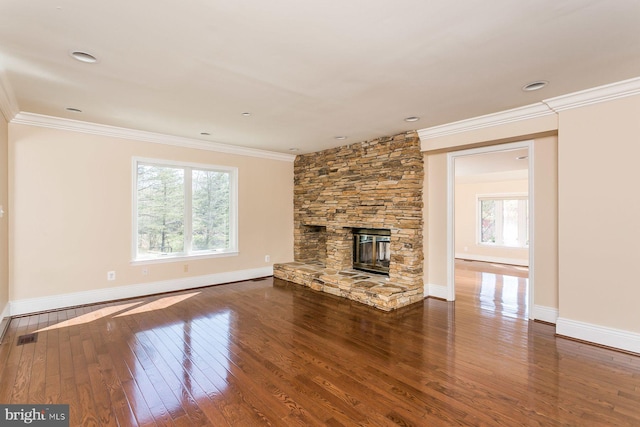 unfurnished living room with dark wood-type flooring, a stone fireplace, and crown molding