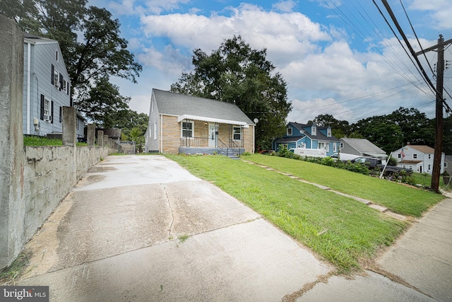 bungalow featuring covered porch and a front yard