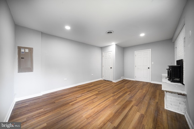 interior space featuring a brick fireplace, electric panel, and dark hardwood / wood-style flooring