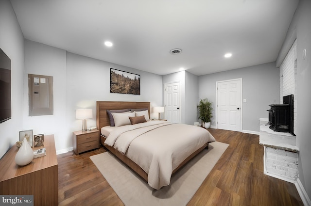 bedroom featuring a fireplace, electric panel, and dark hardwood / wood-style flooring