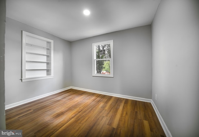 spare room with built in features and dark hardwood / wood-style floors