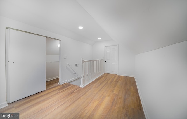 additional living space with light hardwood / wood-style floors and lofted ceiling