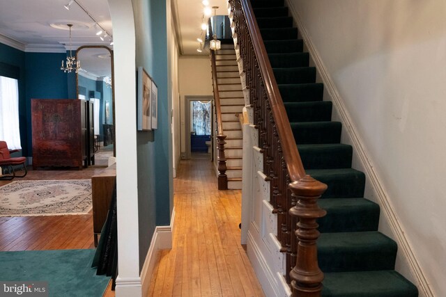 19 S Stricker St, Baltimore, MD 21223 - stairway with crown molding, a chandelier, a wealth of natural light, and hardwood / wood-style floors
