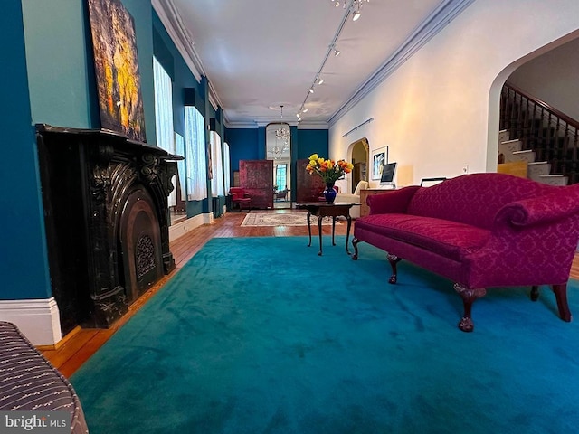 living area featuring arched walkways, wood finished floors, ornamental molding, stairway, and track lighting