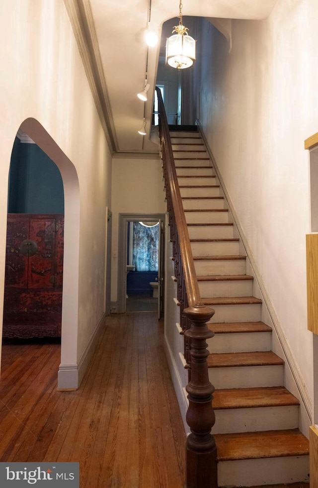 19 S Stricker St, Baltimore, MD 21223 - stairs featuring wood-type flooring, arched walkways, baseboards, and crown molding