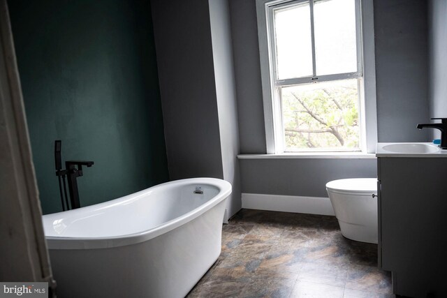 19 S Stricker St, Baltimore, MD 21223 - full bath with vanity, toilet, baseboards, a freestanding bath, and stone finish flooring