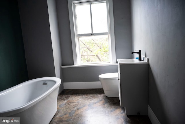 19 S Stricker St, Baltimore, MD 21223 - bathroom with vanity, baseboards, toilet, and a soaking tub