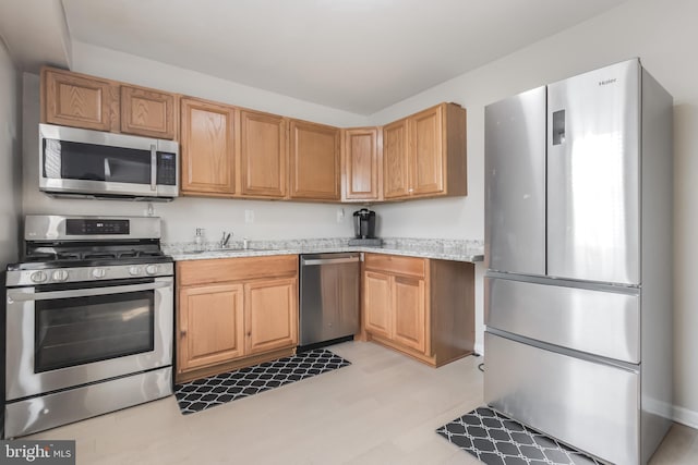 kitchen with appliances with stainless steel finishes, sink, and light stone countertops