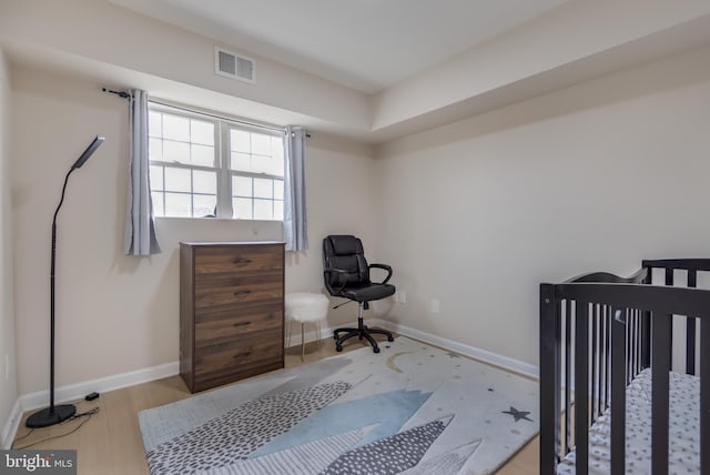 bedroom featuring light hardwood / wood-style floors and a crib