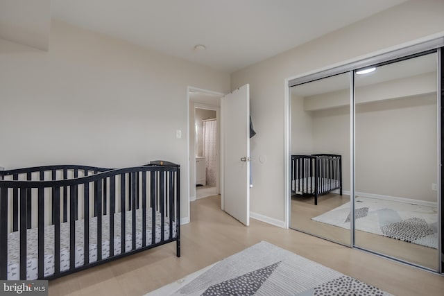 bedroom with a closet, a nursery area, and light wood-type flooring