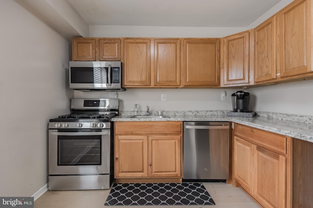 kitchen featuring sink, light stone counters, and stainless steel appliances