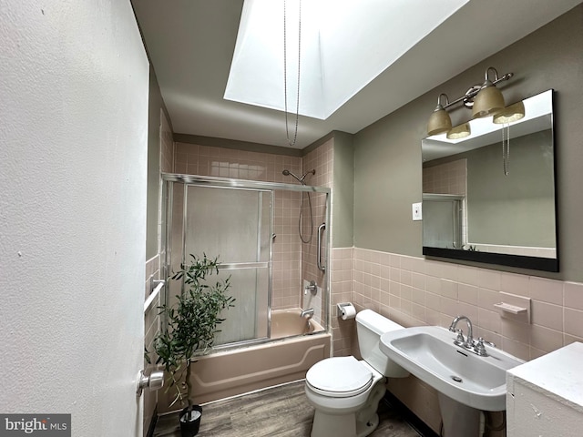 full bathroom with enclosed tub / shower combo, sink, hardwood / wood-style flooring, tile walls, and toilet