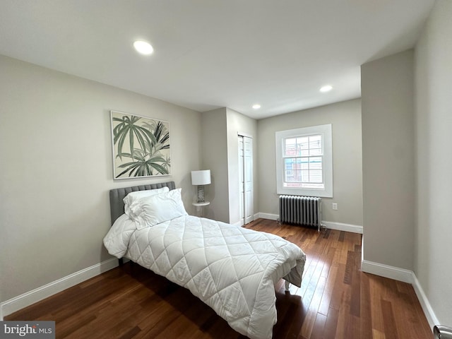 bedroom with dark hardwood / wood-style floors and radiator heating unit