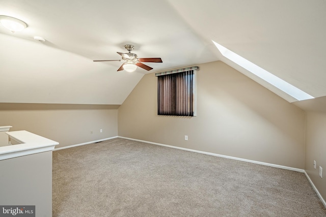 additional living space featuring carpet floors, ceiling fan, and vaulted ceiling with skylight