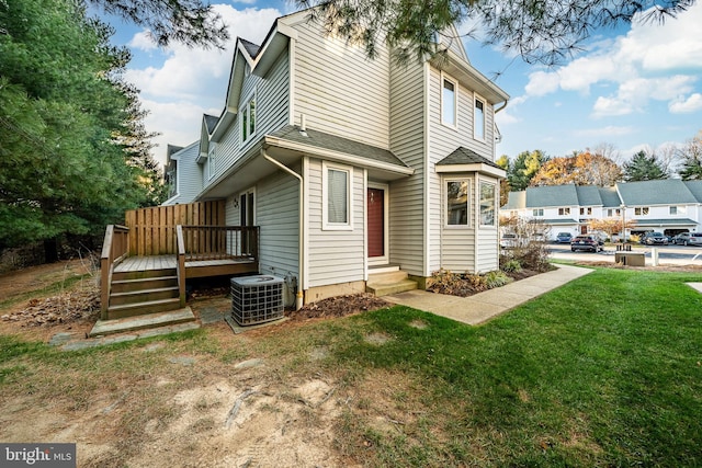 view of side of home featuring a deck, central AC unit, and a lawn