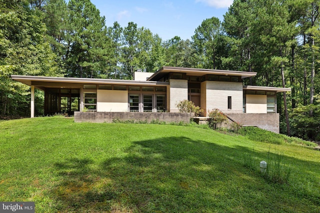 view of front of home featuring a chimney, a front lawn, and brick siding